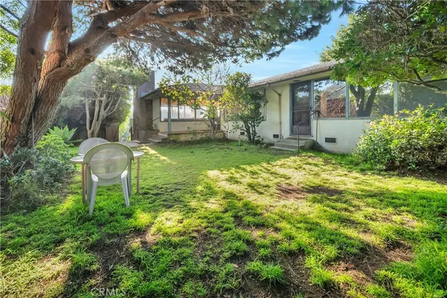 a backyard of a house with large trees and plants