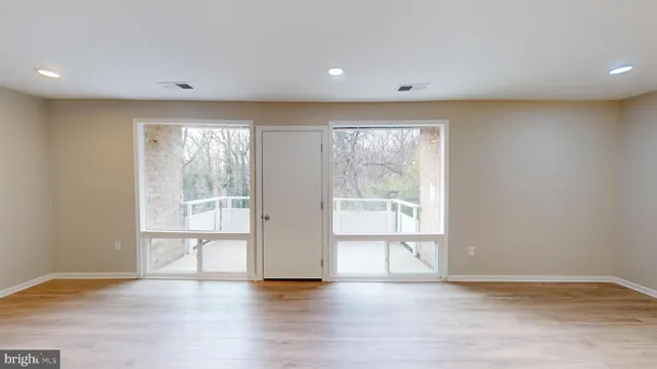 a view of an empty room with a window and wooden floor