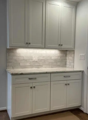 a kitchen with granite countertop white cabinets and a sink