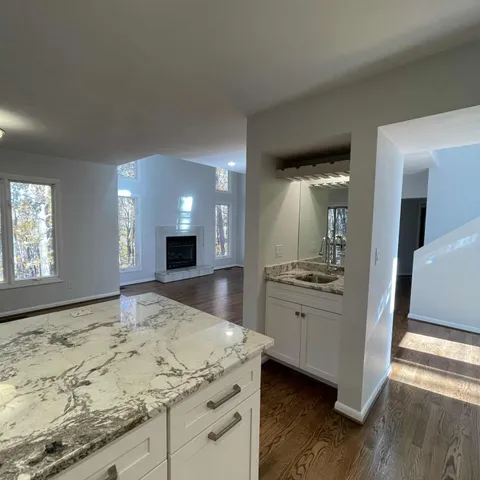 a bathroom with a granite countertop sink a large mirror and a refrigerator