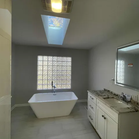 a spacious bathroom with a tub sink and mirror