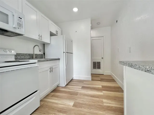 a kitchen with white cabinets and white appliances