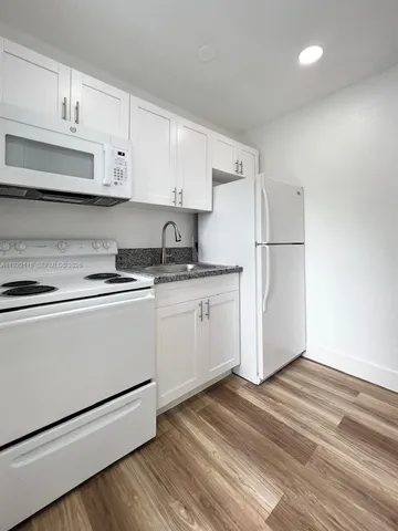 a kitchen with granite countertop white cabinets and white appliances