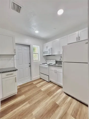 a kitchen with white cabinets and white appliances