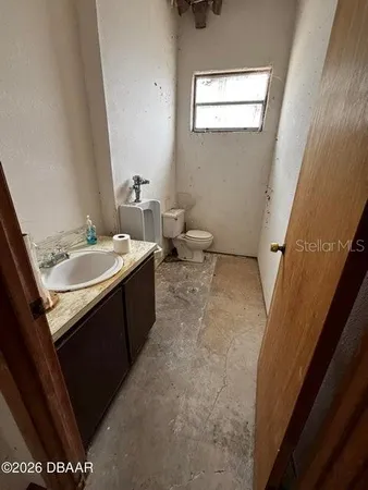 a bathroom with a sink a toilet a mirror and a window