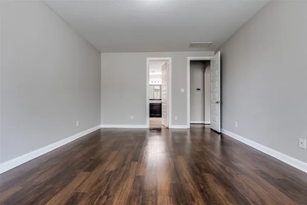 a view of an empty room with wooden floor and window