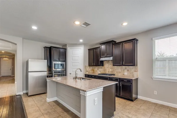 a kitchen with stainless steel appliances kitchen island granite countertop a refrigerator stove and sink