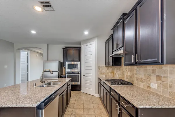 a kitchen with stainless steel appliances granite countertop a sink stove and refrigerator