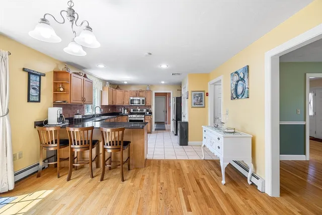 a living room with stainless steel appliances kitchen island granite countertop furniture and a wooden floor