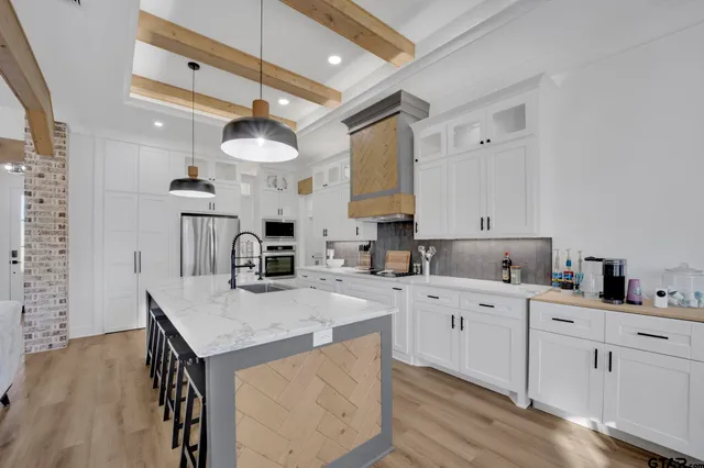 a kitchen with a sink dishwasher and white cabinets with wooden floor