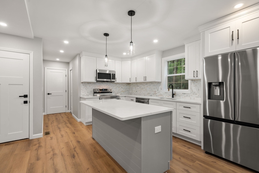 75 Hiland Road Charlton, MA 01507 - Photo 12 of 38 a kitchen with stainless steel appliances granite countertop a refrigerator a sink dishwasher a stove and white cabinets with wooden floor