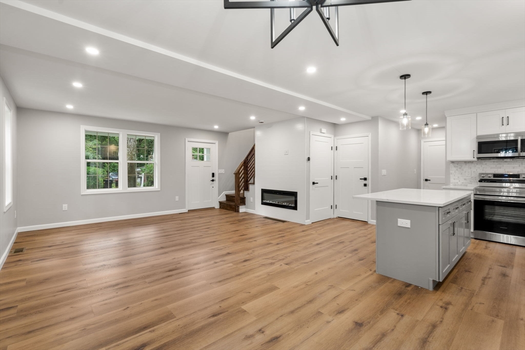 75 Hiland Road Charlton, MA 01507 - Photo 5 of 38 a large kitchen with kitchen island a sink dishwasher stove and white cabinets with wooden floor