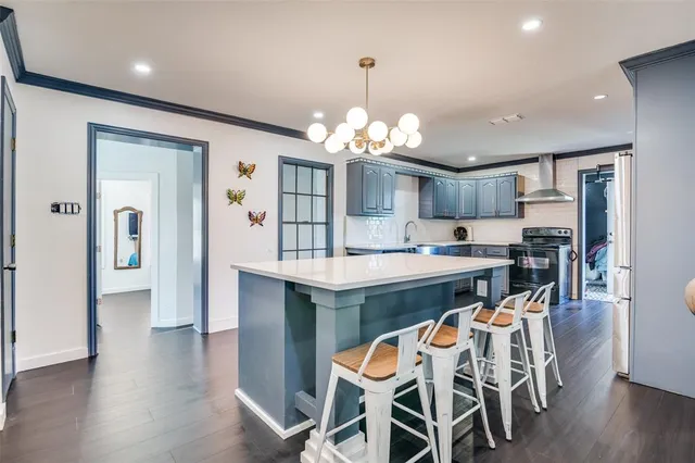 a kitchen with stainless steel appliances a dining table chairs refrigerator and cabinets