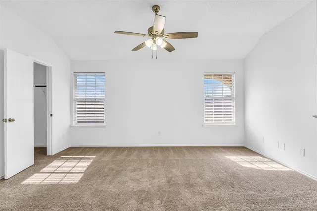 a view of an empty room with chandelier fan
