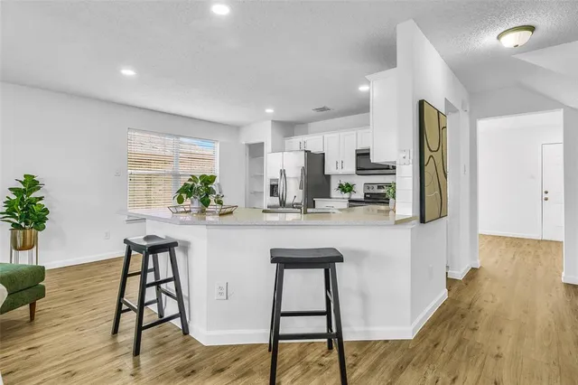 a kitchen with stainless steel appliances kitchen island granite countertop wooden floor and sink