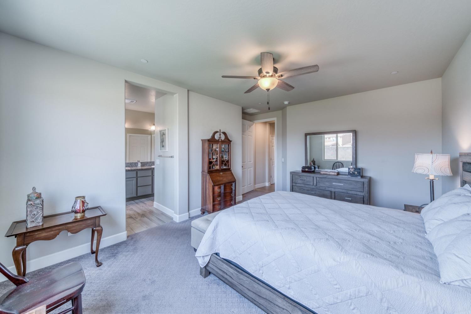 1009 Skylar Lane Clovis, CA 93619 - Photo 18 of 32 a spacious bedroom with a bed and a chandelier