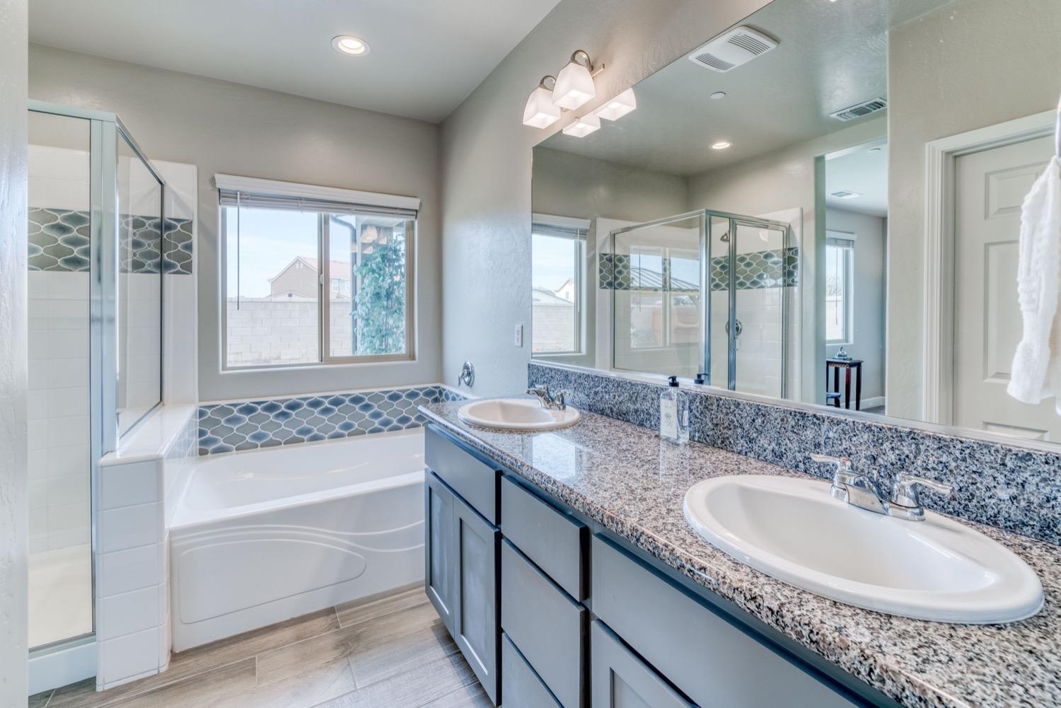 1009 Skylar Lane Clovis, CA 93619 - Photo 19 of 32 a bathroom with a granite countertop tub double vanity and a sink