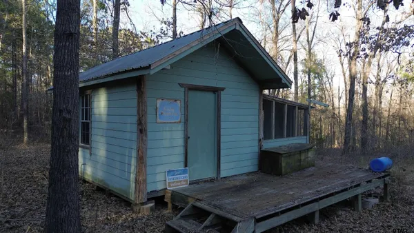 a backyard of a house with wooden fence and large trees
