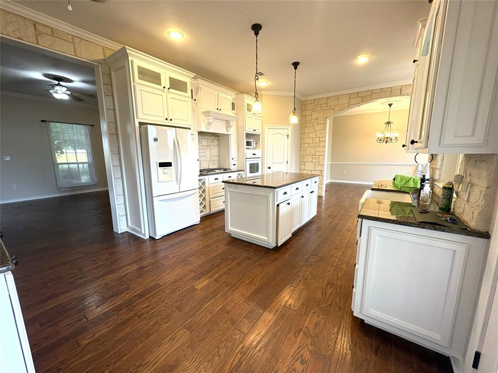 1170 Brazos Loop Gholson, TX 76705 - Photo 10 of 37 Kitchen featuring wood-finish flooring, white cabinetry, a central island with dark countertop, and integrated appliances