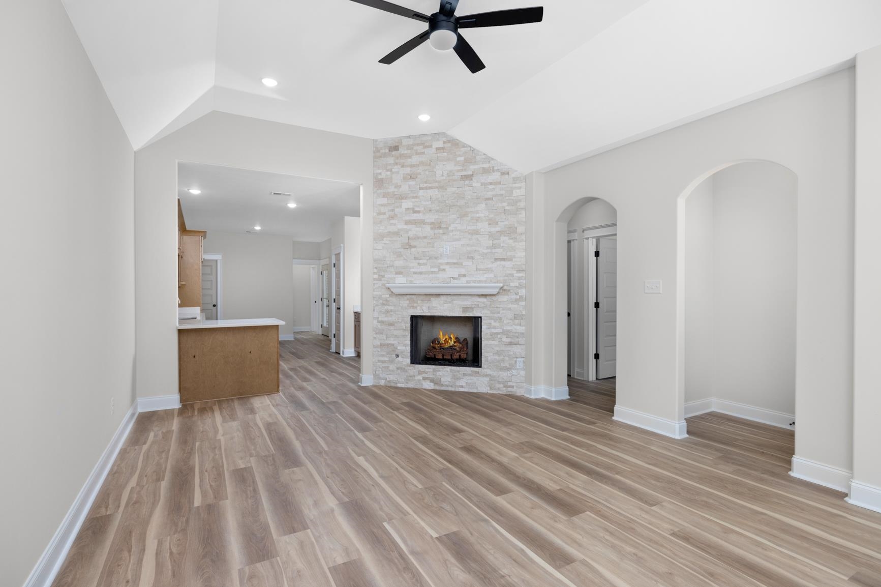 319 North Maple Street Covington, TN 38019 - Photo 7 of 32 Unfurnished living room with lofted ceiling, a stone fireplace, a ceiling fan, light wood-style flooring, and recessed lighting