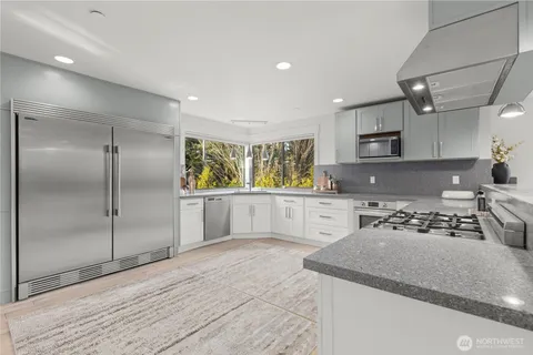 a kitchen with stainless steel appliances granite countertop a sink refrigerator and cabinets