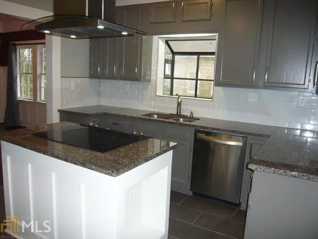 a kitchen with granite countertop a sink a counter top space and cabinets