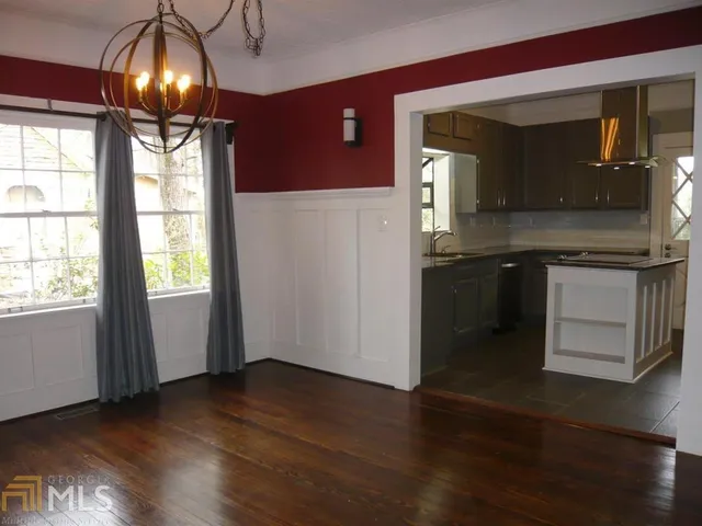 a view of a livingroom with wooden floor and a kitchen