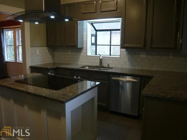 a kitchen with granite countertop stainless steel appliances a sink stove top oven and cabinets