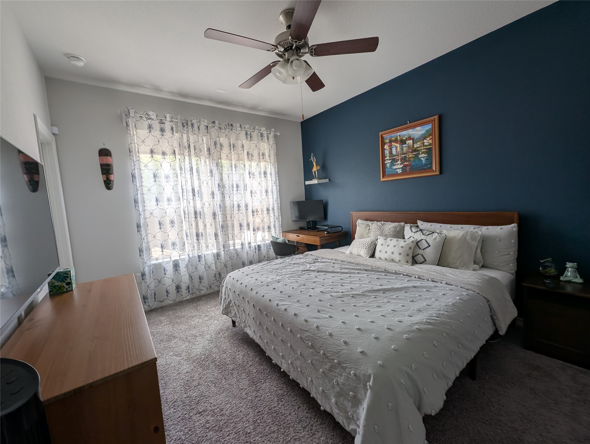 14502 McCoy Loop Austin, TX 78717 - Photo 11 of 26 Bedroom featuring a dark accent wall, ceiling fan with light fixture, and textured carpet flooring