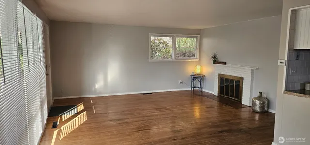an empty room with windows fireplace and wooden floor