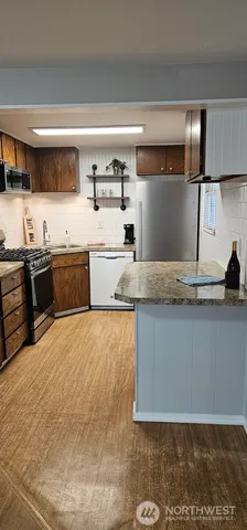 a large kitchen with stainless steel appliances granite countertop a sink and stove