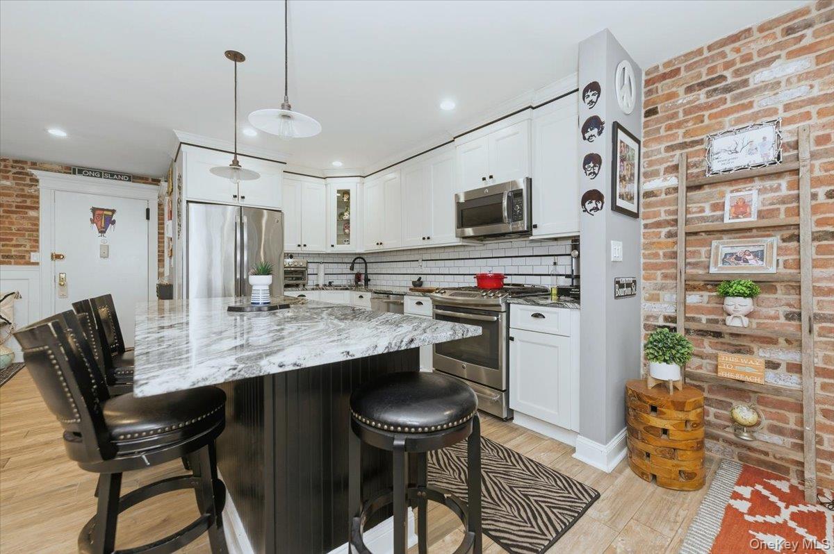 711 Shore Road, Unit 1J Long Beach, NY 11561 - Photo 3 of 22 a kitchen with stainless steel appliances a table chairs and a refrigerator