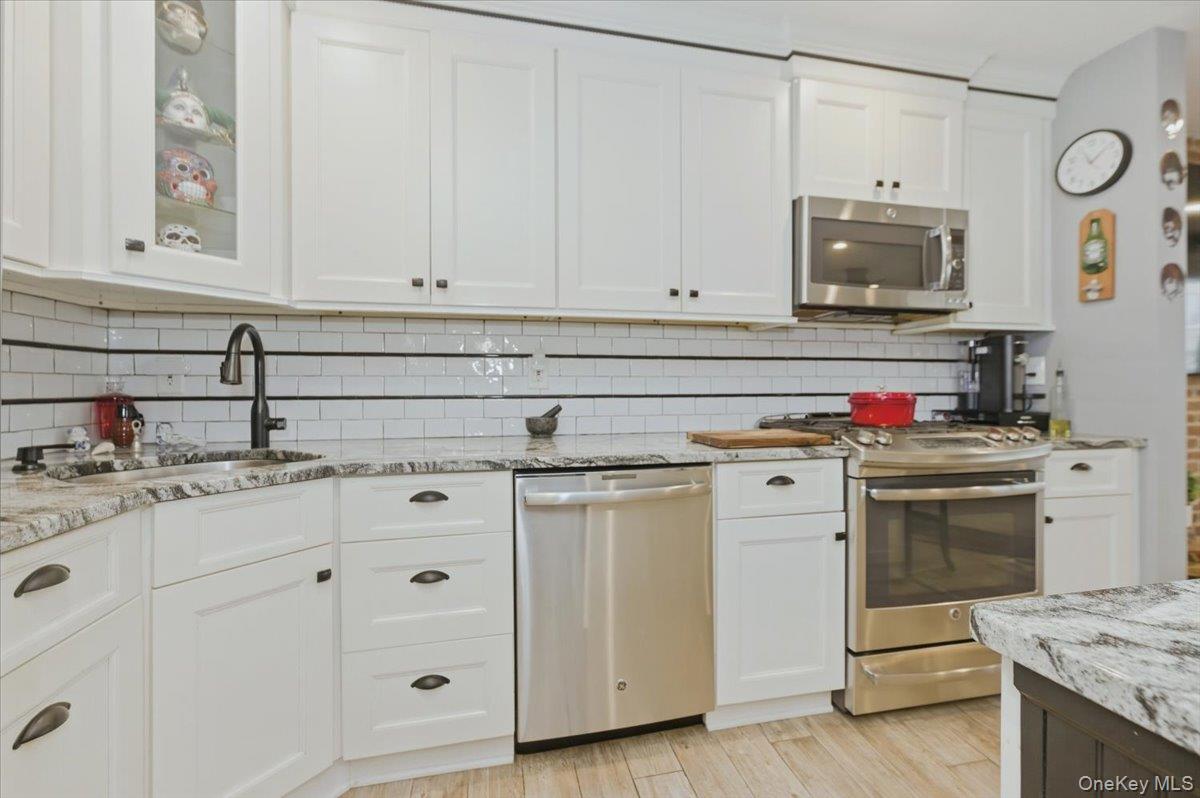 711 Shore Road, Unit 1J Long Beach, NY 11561 - Photo 4 of 22 a kitchen with granite countertop white cabinets and stainless steel appliances