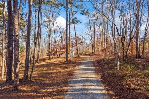 a view of small white house with a large tree and wooden fence