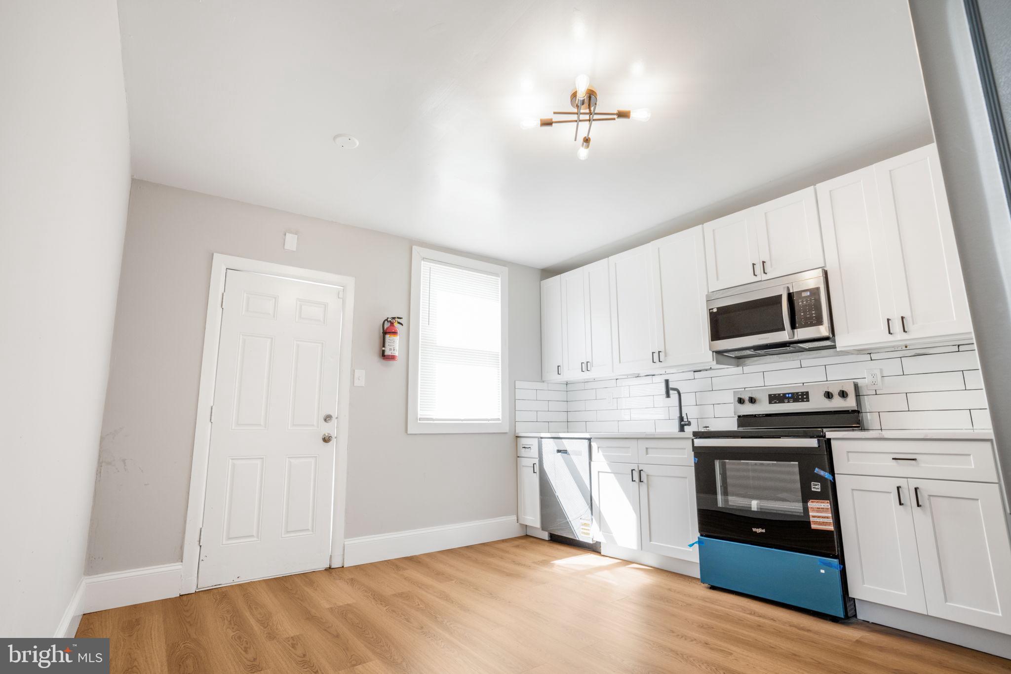 246 Chestnut Street Mount Holly, NJ 08060 - Photo 20 of 25 a kitchen with stainless steel appliances a stove top oven a sink a refrigerator white cabinets and wooden floor