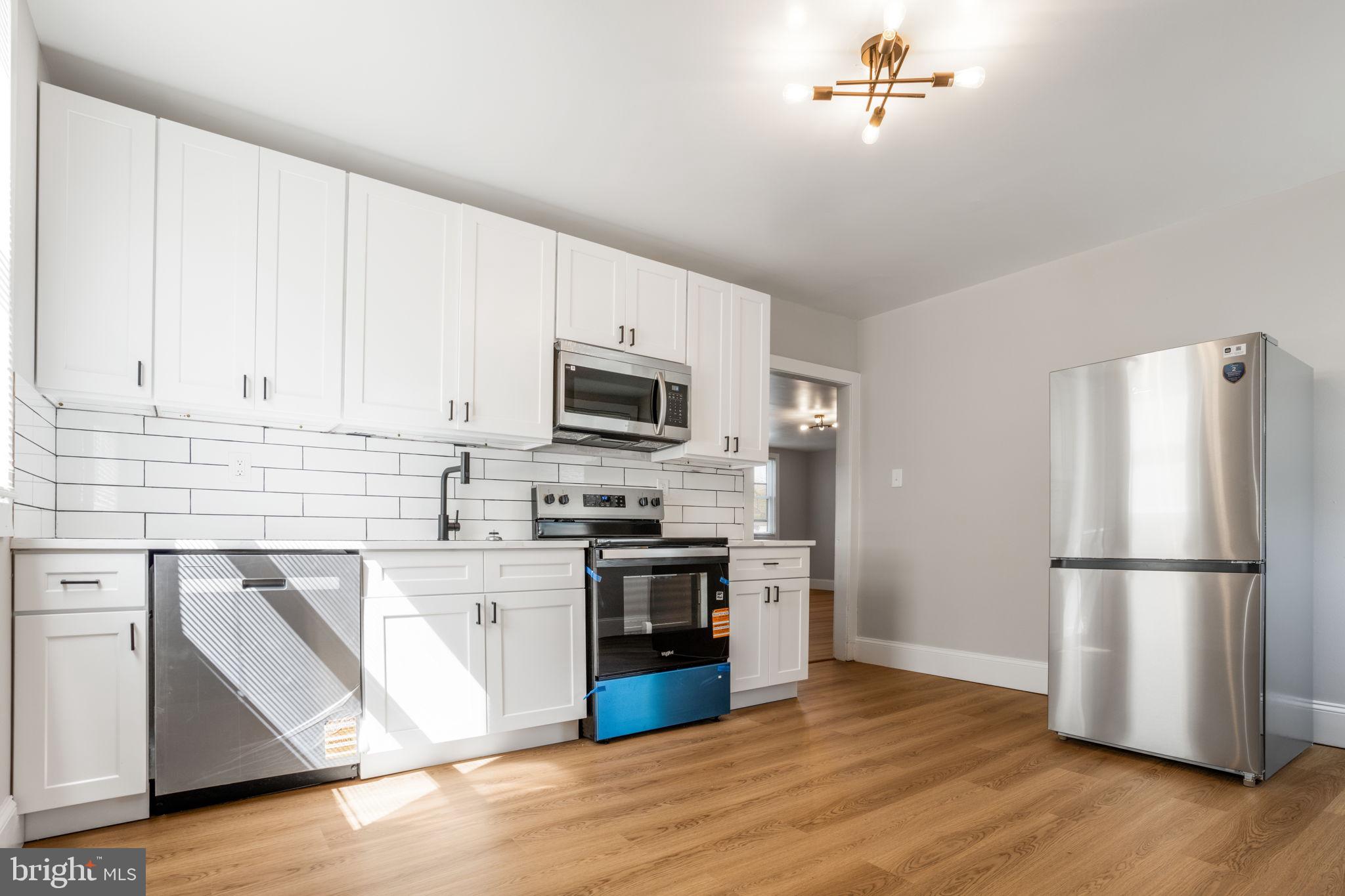 246 Chestnut Street Mount Holly, NJ 08060 - Photo 23 of 25 a kitchen with stainless steel appliances granite countertop a refrigerator stove a sink and white cabinets with wooden floor