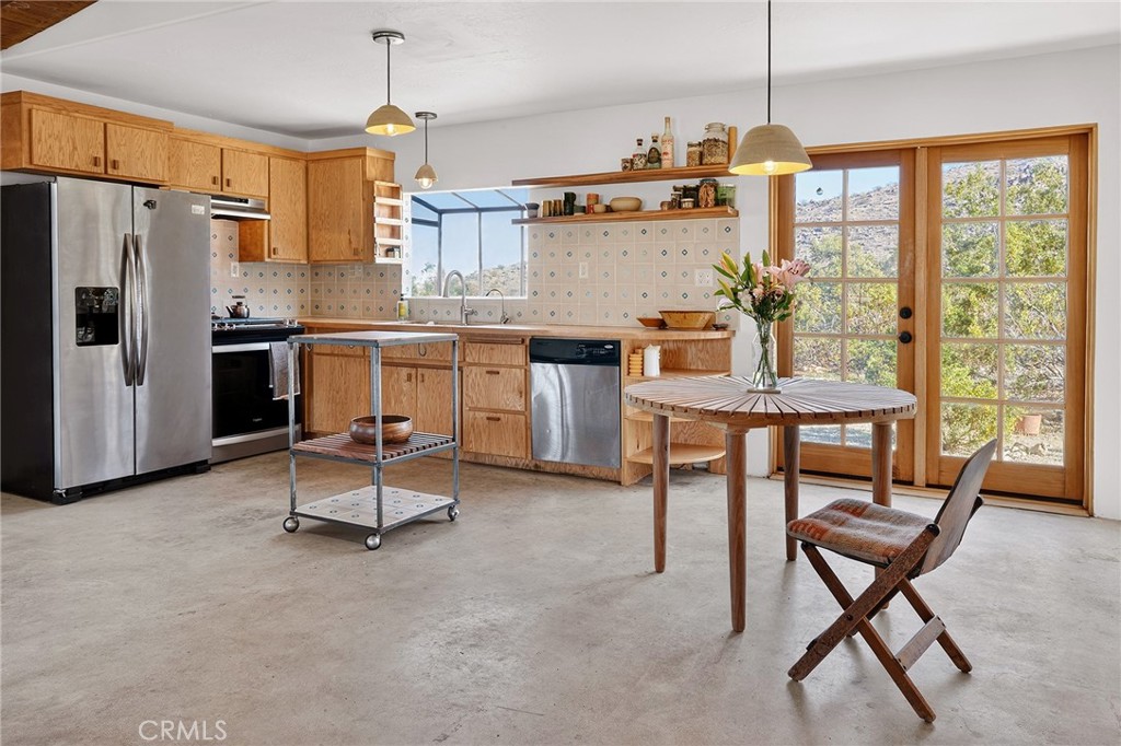 60473 Starlight Road Joshua Tree, CA 92252 - Photo 11 of 39 a kitchen with a table chairs refrigerator and cabinets