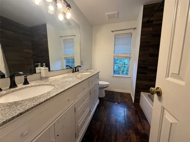 a bathroom with a granite countertop double vanity sink a mirror and a shower
