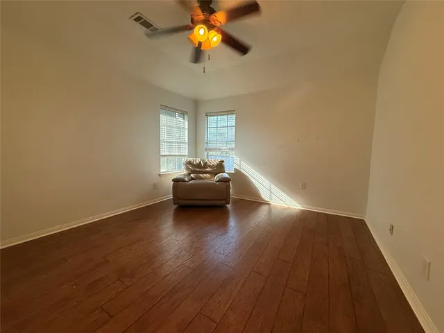 a view of a livingroom with wooden floor and a ceiling fan