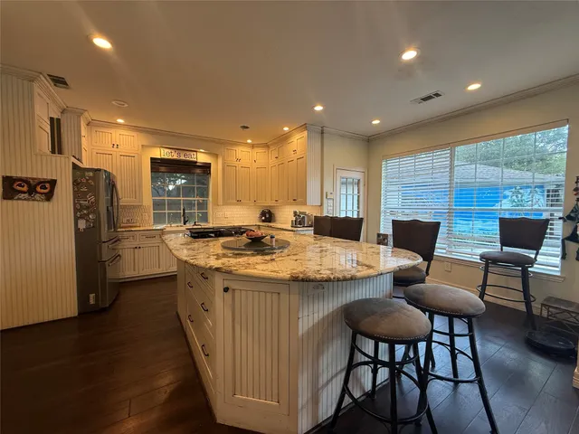 a kitchen with stainless steel appliances granite countertop a kitchen island a hardwood floor and a sink