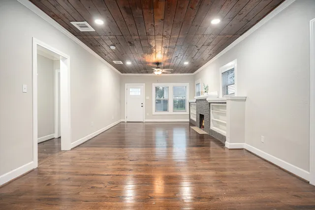 an empty room with wooden floor and a kitchen
