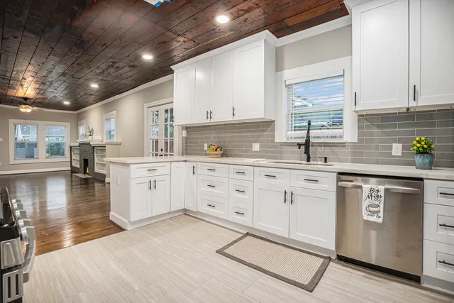a kitchen with white cabinets a sink dishwasher and white appliances with wooden floor
