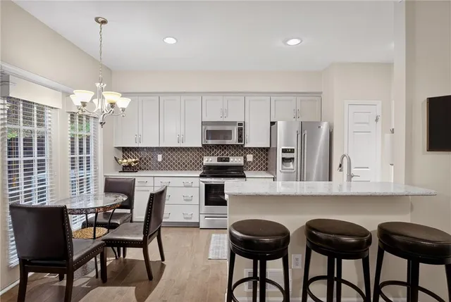 a kitchen with stainless steel appliances granite countertop a white table chairs and a refrigerator