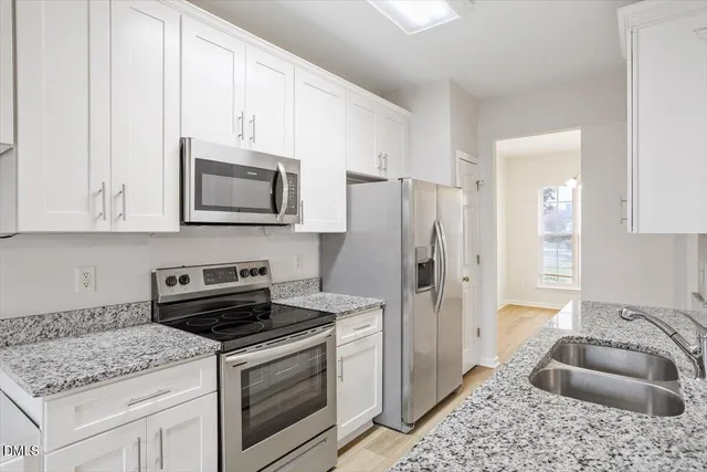 a kitchen with granite countertop a sink stove and refrigerator