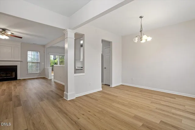 an empty room with wooden floor fireplace and windows