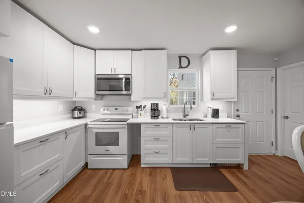 a kitchen with granite countertop white cabinets and white appliances