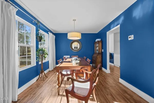 a dining room with wooden floor a chandelier a wooden table and chairs