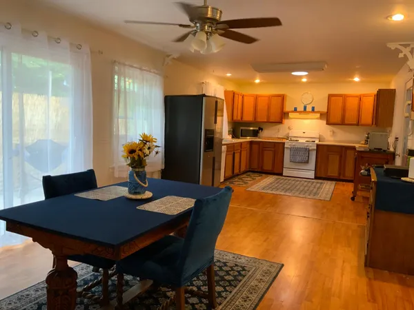 a kitchen with stainless steel appliances granite countertop a stove a refrigerator a sink a dining table and chairs with wooden floor
