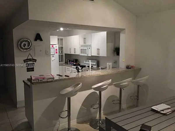 a room with chairs and view of kitchen