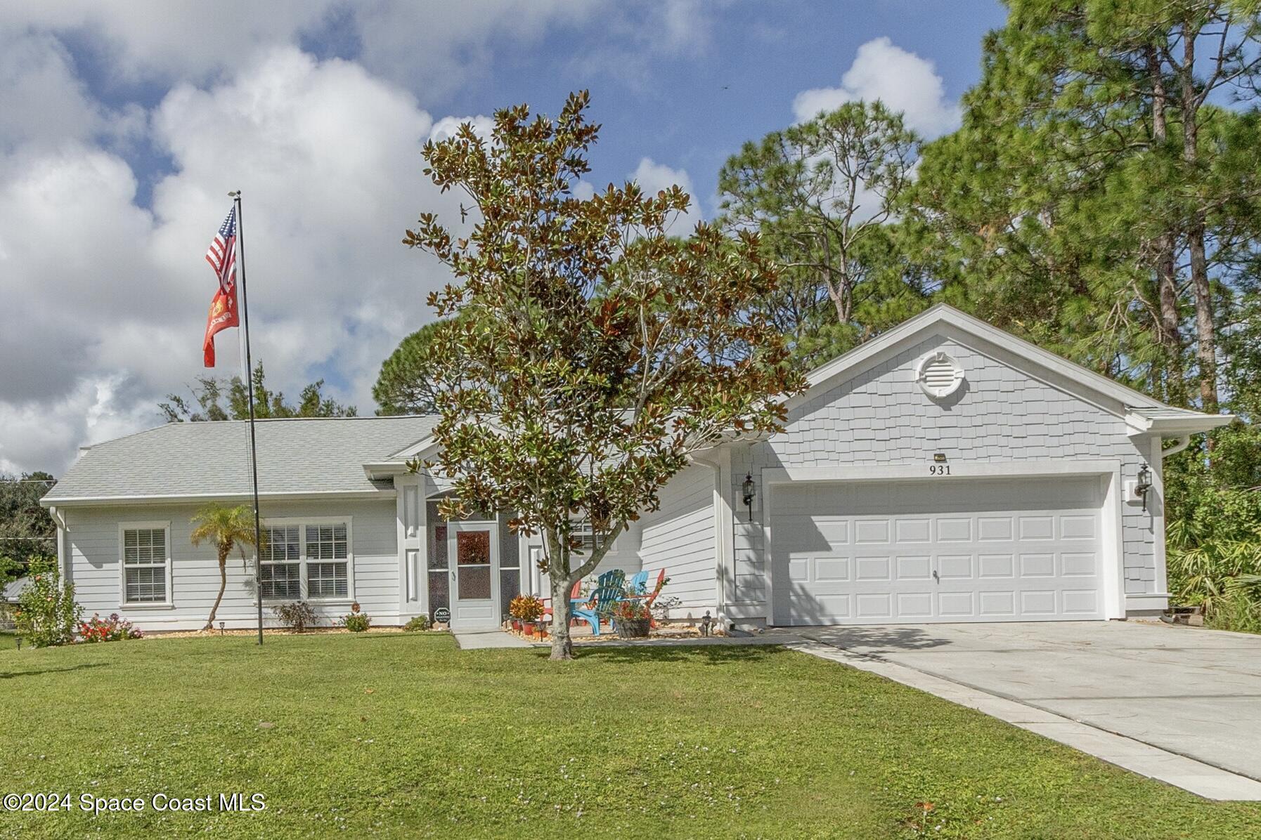 931 Pandora Road Southeast Palm Bay, FL 32909 - Photo 1 of 34 a front view of a house with a garden and trees